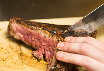 A knife slicing through a delicious grilledT Bone steak