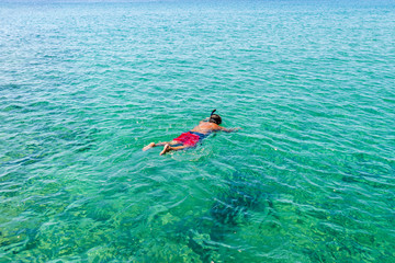 Man swimming in the aegean sea near one of the most beautiful be