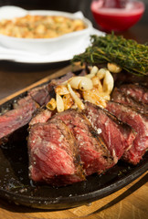 A selection of grilledT Bone steak pieces and roasted garlic, off the bone on a metal plate