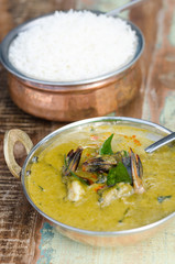 A delicious spicy prawn green curry, served with sticky rice in a rustic metal pan.
