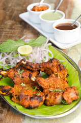Delicious tandoori chicken starter, served with lime, onion, mint, yoghurt and sauces, on a banana leaf base.