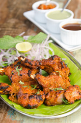 Delicious tandoori chicken starter, served with lime, onion, mint, yoghurt and sauces, on a banana leaf base.