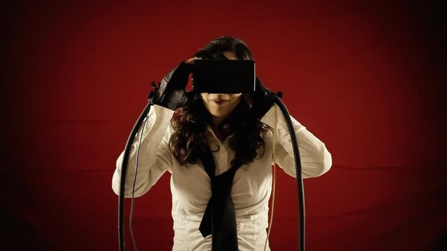A girl wearing a virtual reality headset and wired gloves, looking bored. Front shot.