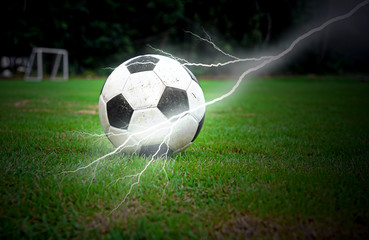 Football on green grass with lightning