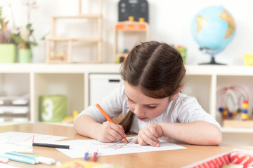 cute little girl drawing with felt-tip pen in kindergarten classroom