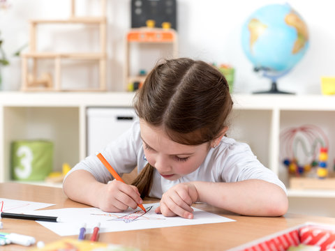 cute little girl drawing in preschool classroom
