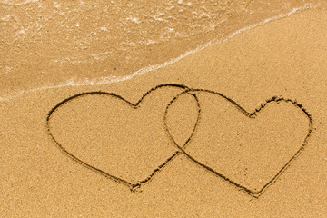 Two hearts drawn on the sand of a sea beach.