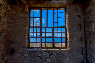 Fototapeta na wymiar Big window to the sea on an abandoned old factory.