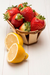 Fototapeta na wymiar Strawberries in a small basket and lemon