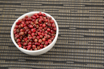 Peppercorns mixed in bowl on dark background. Top view with copy space.
