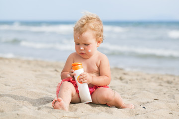 Adorable girl at beach applying sunblock cream