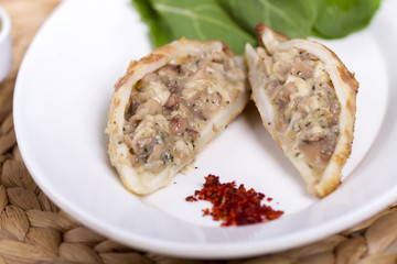 Plate of stuffed cuttlefish inside cheese, mushroom and seafood serving with aubergine salad