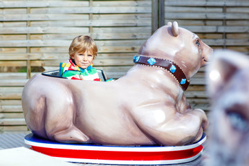 Little kid boy on carousel in amusement park