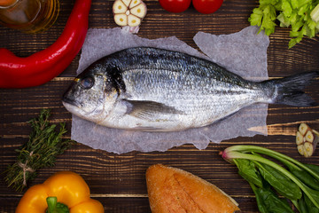 Overhead View of Dorado Fish, Spinach, Bell Pepper, Tomato Cherry, Bread, Garlic, Thyme, Olive Oil, Glass of White Wine and Celery on Dark Rustic Wooden Background