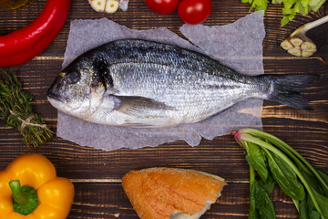 Overhead View of Dorado Fish, Spinach, Bell Pepper, Tomato Cherry, Bread, Garlic, Thyme, Olive Oil, Glass of White Wine and Celery on Dark Rustic Wooden Background