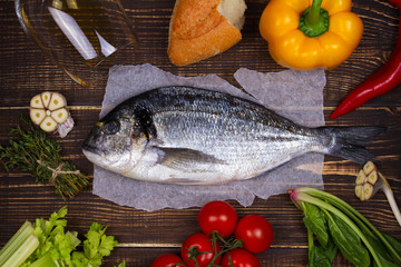 Overhead View of Dorado Fish, Spinach, Bell Pepper, Tomato Cherry, Bread, Garlic, Thyme, Olive Oil, Glass of White Wine and Celery on Dark Rustic Wooden Background