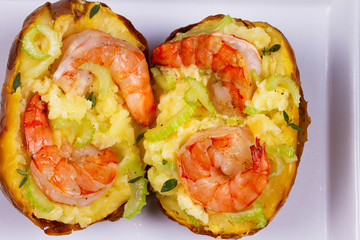 Stuffed potato with shrimps, celery, cheese and thyme. View from above, top studio shot
