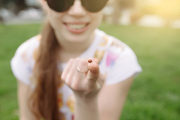 Happy girl holding ladybug on finger and smile on grass