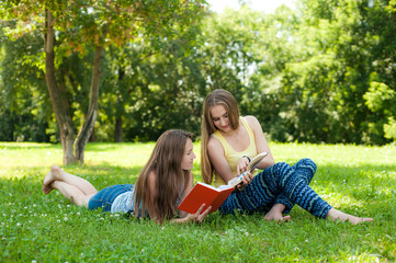 Fototapeta premium Two girls read the book in the park