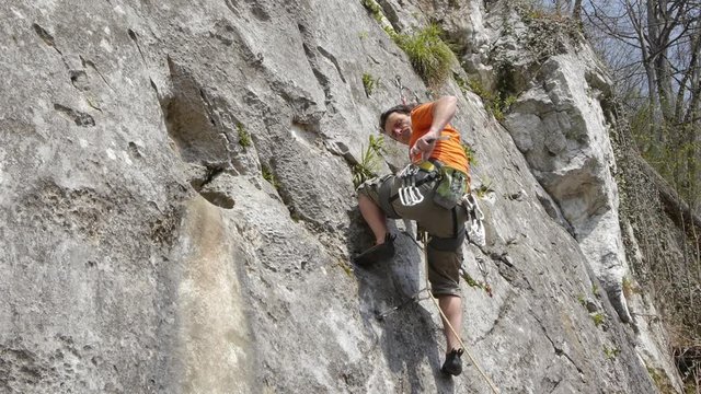 Male rock climber securing with carabiner and rope. Low angle view.
