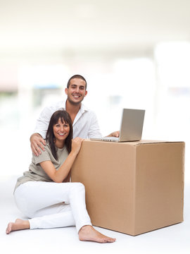 beautiful young love couple with box and laptop in a interior design