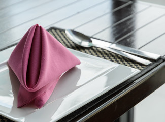 Folded pink napkin on white plate