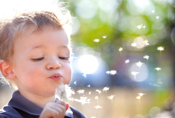 happy smiling child playing with dandelion outdoor in a garden