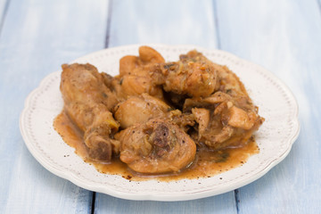 boiled chicken with beer sauce in white plate on blue wooden background