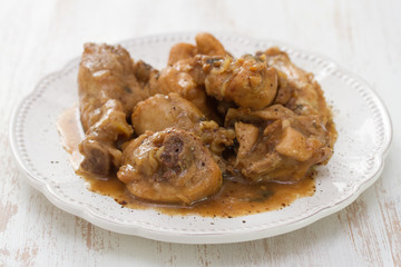 boiled chicken with beer sauce in white plate on white wooden background