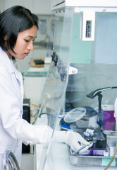 technician works under safety hood of plastic in hospital laboratory