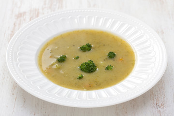 vegetable soup with broccoli on white dish on white wooden background