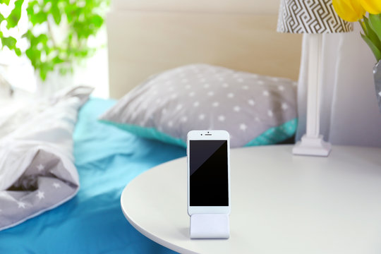 Smart Phone With Stand On A Bedside Table In A Room