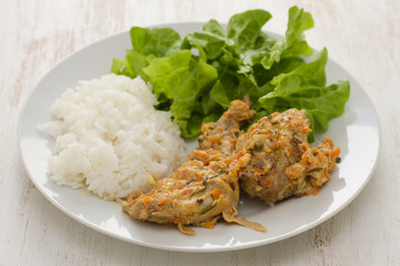 rabbit with boiled rice and salad on plate on white wooden background
