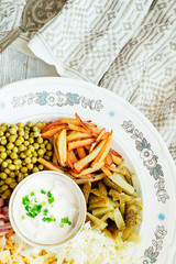 
salad with lots of ingredients - roasted potatoes, green peas , boiled eggs , ham , cabbage , pickled cucumbers , green onions , and mayonnaise on a wooden background 