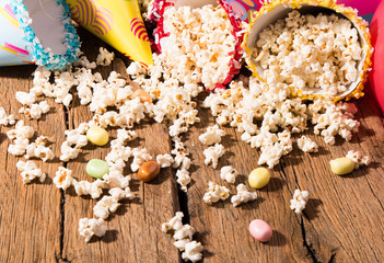 Salt popcorn, party hat and candy on the wooden table,