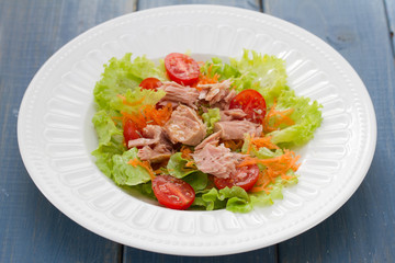 tuna salad on white plate on blue wooden background