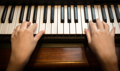Closeup of child's hands playing on the piano