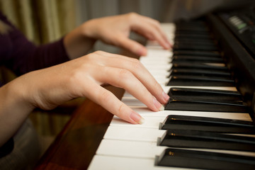 Fototapeta na wymiar Closeup of young woman playing on piano