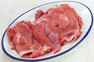 raw turkey on white dish on white wooden background