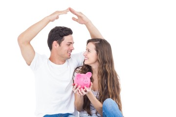 Young couple sitting on floor with piggy bank