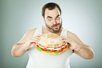 fat funny man eat a huge sandwich isolated on grey