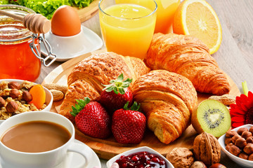 Breakfast consisting of croissants, coffee, fruits, orange juice