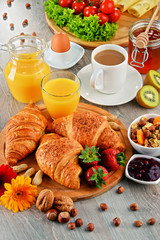 Breakfast consisting of croissants, coffee, fruits, orange juice