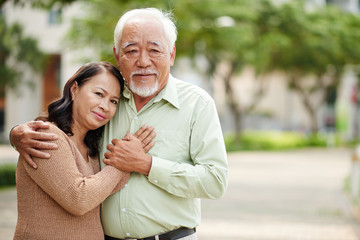 Fototapeta premium Portrait of hugging aged Vietnamese couple outdoors