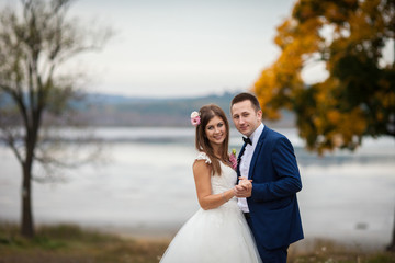 elegant stylish groom with his happy gorgeous brunette bride on