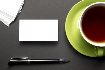 Business card blank over coffee cup and pen at office table. Corporate stationery branding mock-up