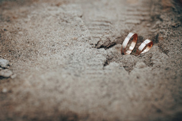 golden gorgeous wedding rings in sand on the  background of a la