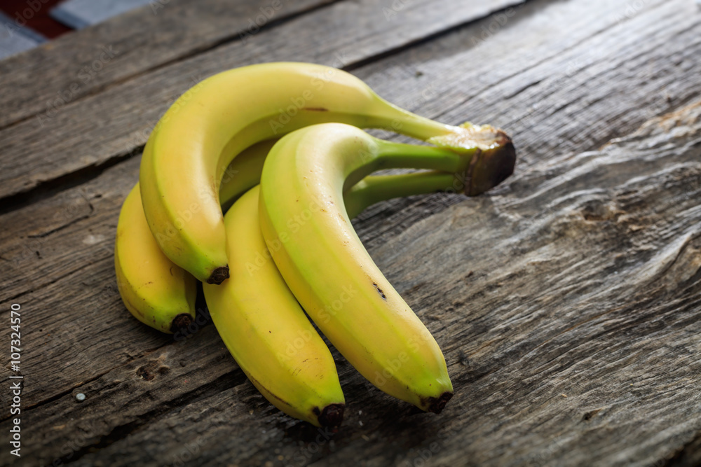 Wall mural fresh yellow bananas, on wooden surface