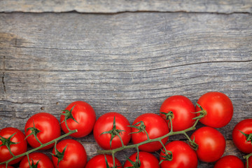 Bunches of red cherry tomatoes, on wooden surface with copy-space