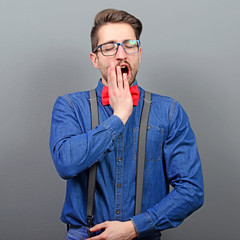 Portrait of man yawning against gray background